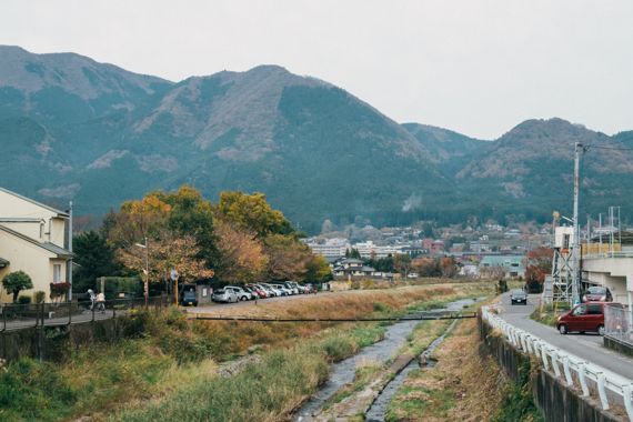 높다란 산 아래 낮은 건물이 옹기종기 모여있는 유후인의 전경. ⓒTayawee Supan on Unsplash