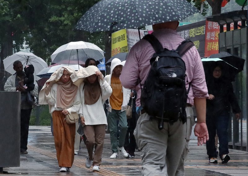 북상하는 기압골의 영향을 받아 수도권 등에 비가 내린 5월 27일 오전 서울 중구 태평로 일대를 지나는 외국인들이 우산과 옷을 이용해 비를 피하고 있다. ⓒ사진 뉴스1