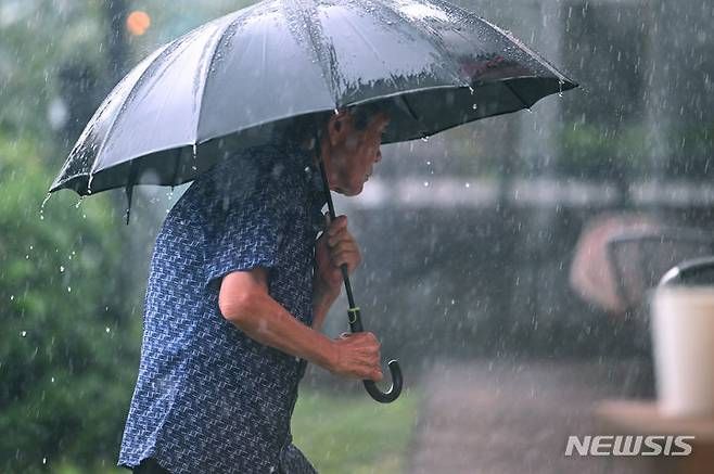 광주 서구 운천저수지 주변에서 한 시민이 우산을 쓴 채 발걸음을 옮기고 있다. ⓒ사진 2024년 7월 8일 뉴시스